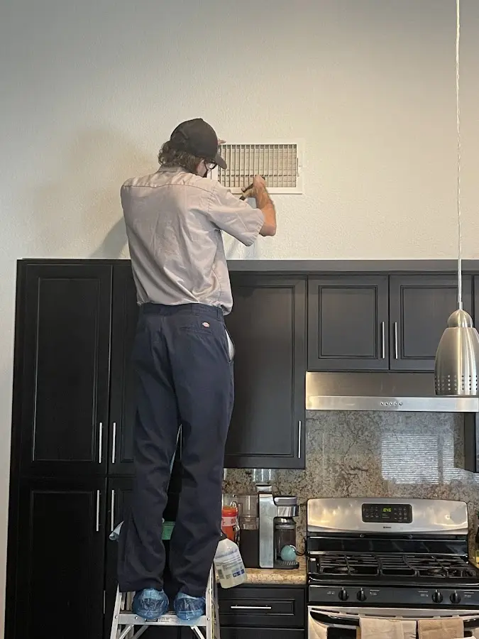 Technician inspecting an air vent during HVAC service in Jackson